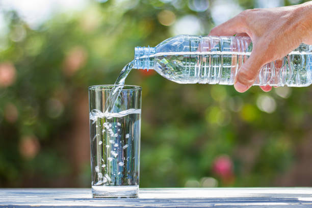istock Man's hand holding bottle water, pouring water into glass 652255804