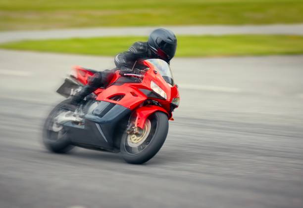 Fast motorbike racing on the race track at high speed. Fast motorbike racing on the race track at high speed. Composite image with heavy image editing. motorbike racing stock pictures, royalty-free photos & images