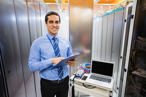 Portrait of happy technician holding clipboard in server room