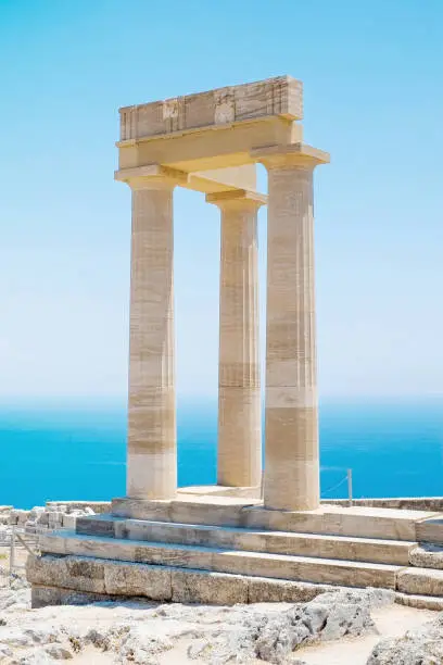 Famous Greek temple pillar against clear blue sky and sea in Lindos Acropolis Rhodes Athena Temple, Greece