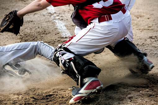 Anonymous youth baseball player slides under the catcher's tag at home plate
