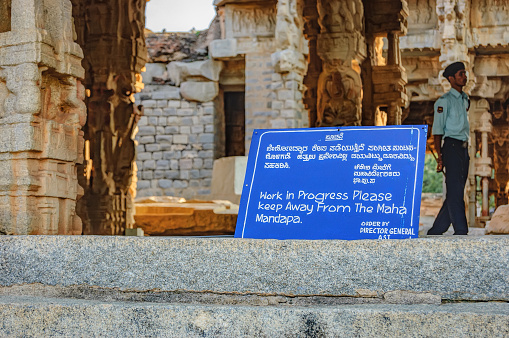 Hampi, India - November 19, 2012: Ancient Indian architecture for restoration. Sign about the restoration work in the courtyard of Vittala Temple in Hampi, Karnataka, India.