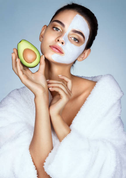 Sensual young girl holding half an avocado in hand.