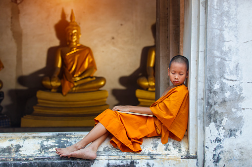 Novice sleeping on the terrace after hard study discipline outside of The Buddha Status. Temple in Thailand.