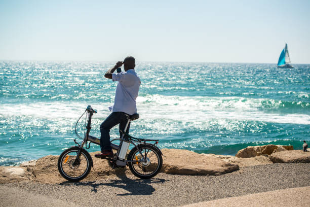 Tel Aviv, Israel - May 12, 2016:  Tel Aviv beaches crowded with people celebrating Independence Day. Man with bicycle doing selfie with mobile phone on the beach