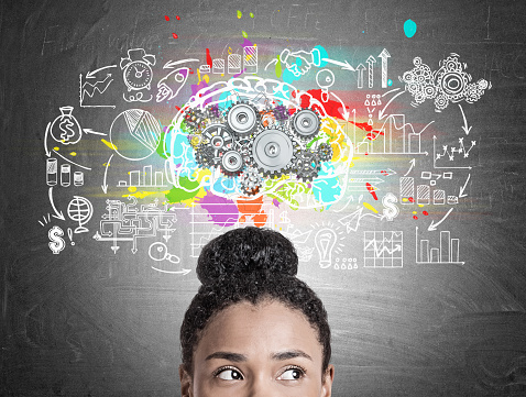 Close up of a head of an African American woman standing near a blackboard with a brain sketch with gears and a startup drawing.