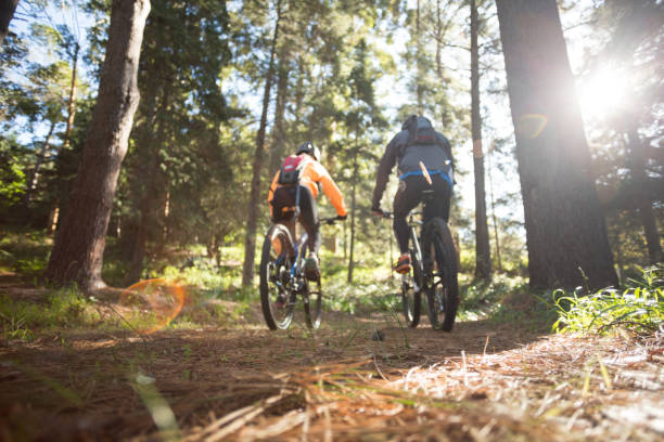 Biker couple riding mountain bike in the forest Biker couple riding mountain bike in the forest at countryside mountain bike stock pictures, royalty-free photos & images
