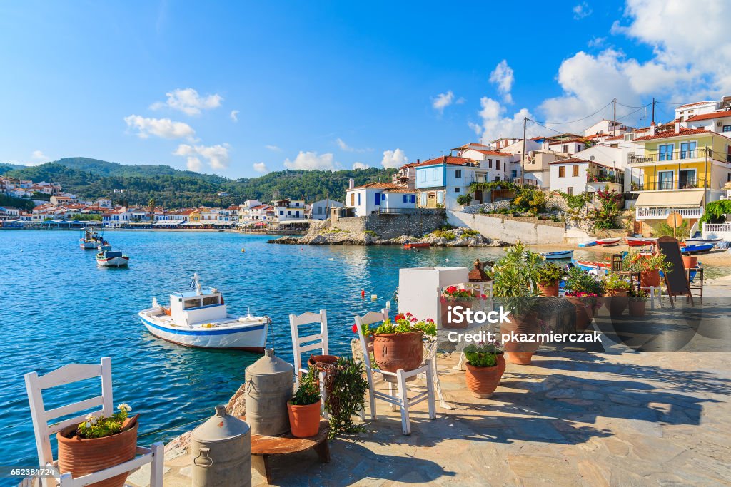 Flower pots on and view of fishing boats anchoring in Kokkari bay, Samos island, Greece Samos is a Greek island in the eastern Aegean Sea, south of Chios, north of Patmos. Greece Stock Photo