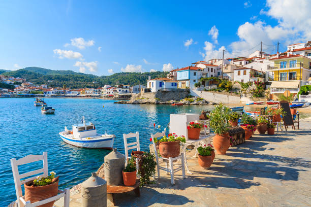 Flower pots on and view of fishing boats anchoring in Kokkari bay, Samos island, Greece Samos is a Greek island in the eastern Aegean Sea, south of Chios, north of Patmos. greece stock pictures, royalty-free photos & images