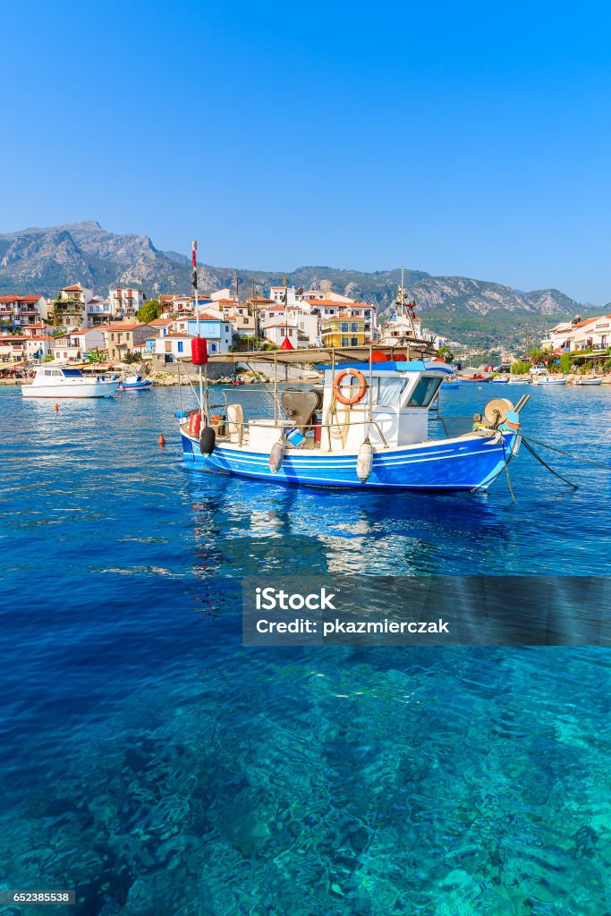 Typical blue and white colour fishing boat on azure crystal clear sea water in Kokkari port, Samos island, Greece Samos is a Greek island in the eastern Aegean Sea, south of Chios, north of Patmos. Patmos Stock Photo