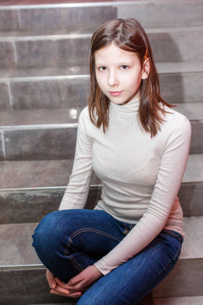 teen girl sitting on stairs. Indoor portrait of a sad teenage girl