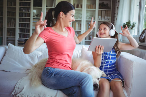 excited mother and daughter using digital tablet and dancing - white dog audio imagens e fotografias de stock