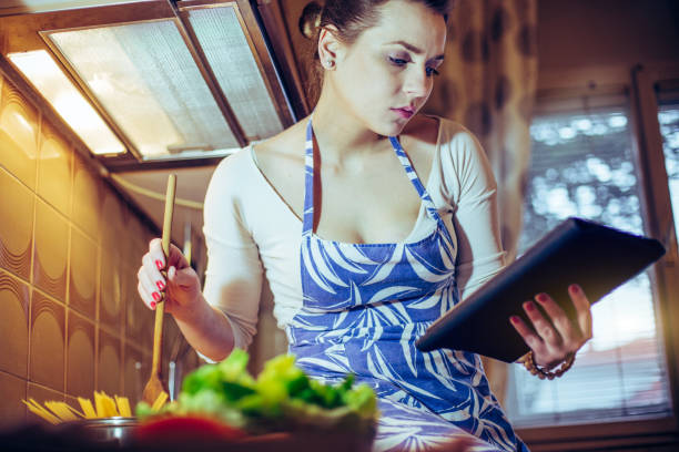 istock Beautiful young woman reading recipe on digital tablet 652489644