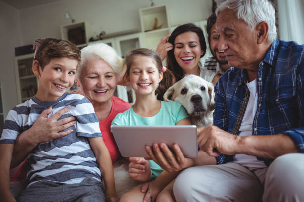 generationsübergreifende familienglück mit digital-tablette im wohnzimmer - grandmother senior adult child multi generation family stock-fotos und bilder