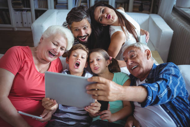 multi-generationen-familie unter einem selfie auf digital-tablette im wohnzimmer - grandmother senior adult child multi generation family stock-fotos und bilder