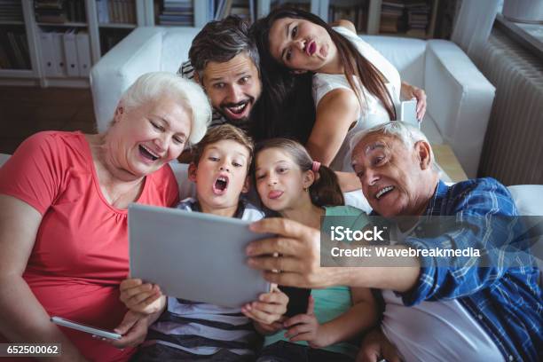 Familia De Múltiples Generaciones Teniendo Un Selfie En Tableta Digital En Sala De Estar Foto de stock y más banco de imágenes de Familia