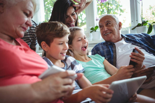 glückliche mehr-generationen-familie sitzen zusammen im wohnzimmer - grandmother senior adult child multi generation family stock-fotos und bilder