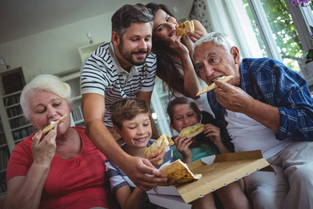 mehr-generationen-familie mit pizza zusammen - grandmother senior adult child multi generation family stock-fotos und bilder