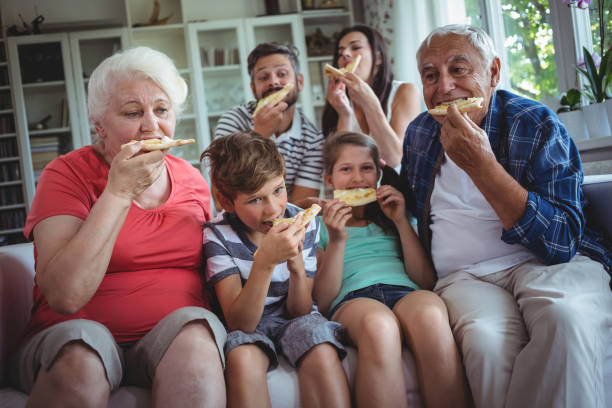 mehr-generationen-familie mit pizza zusammen - grandmother senior adult child multi generation family stock-fotos und bilder