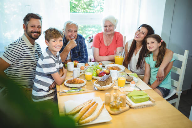 porträt der glückliche mehr-generationen-familie am frühstückstisch sitzen - grandmother senior adult child multi generation family stock-fotos und bilder