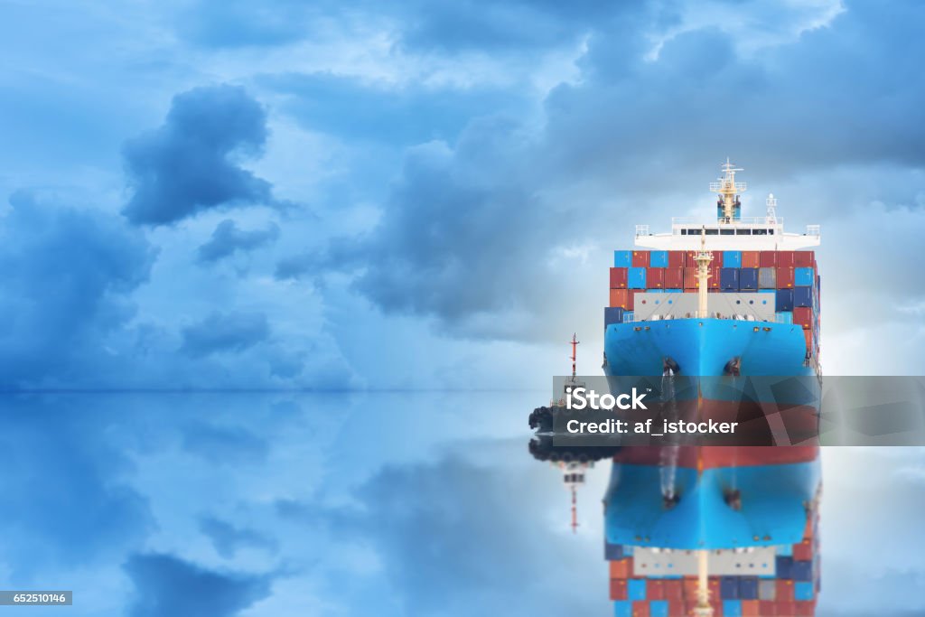 Logistics and transportation of international container cargo ship with port crane bridge in seaport at twilight sky for logistics import export background and transportation industry Container Ship Stock Photo