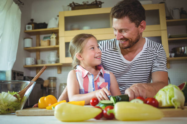 istock Father and daughter smiling at each other while preparing salad 652520836