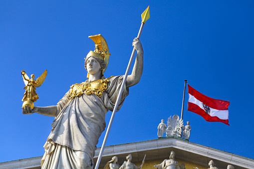 The Athena Fountain (Pallas-Athene-Brunnen) and flag of Austria on Austrian parliament building in capital Vienna.
