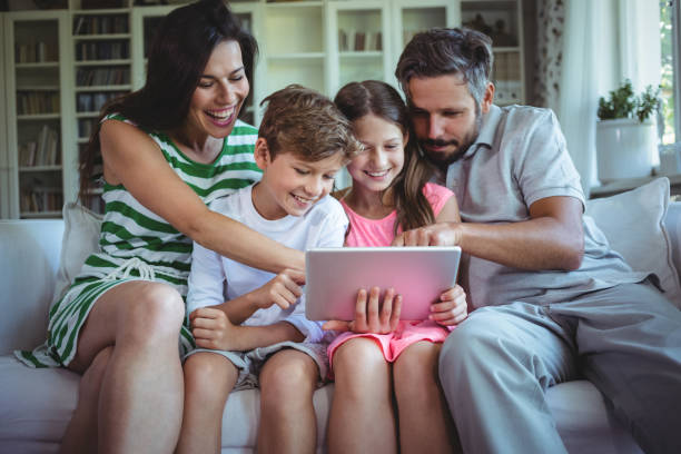 istock Parents sitting on sofa with their children and using digital tablet in living room 652549762