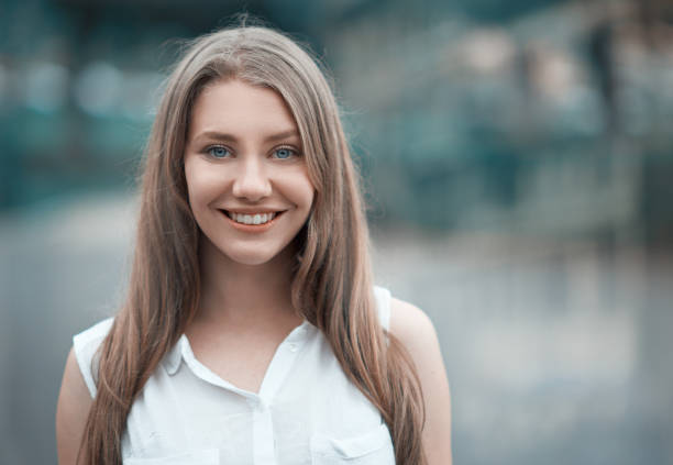 Summer portrait, of beautiful woman with grey eyes,long wavy hair,brown hair,light makeup and pink lipstick,nice smile and white teeth,posing outdoors on the walk to the green Park in Sunny day