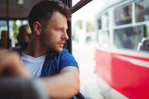 Handsome man looking through window while traveling in bus