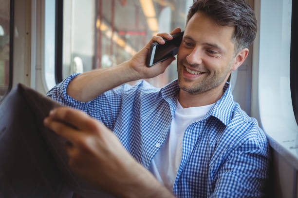 istock Handsome man holding newspaper while talking on mobile phone 652568768