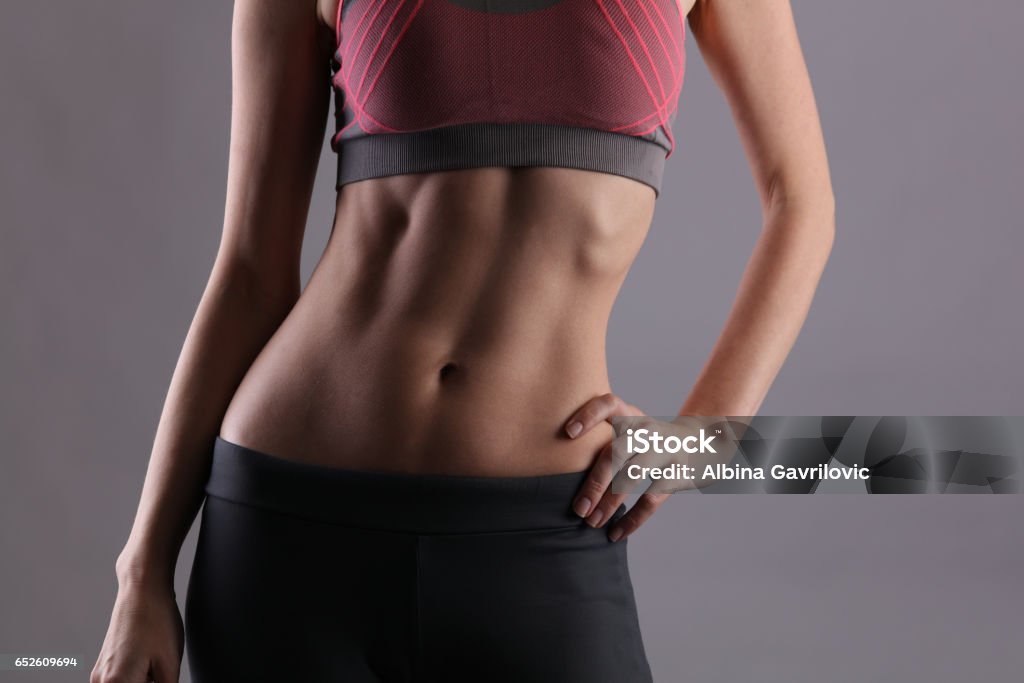 Sport, fit woman. Female with perfect abdomen muscles on grey background. Dieting, fitness, active lifestyle concept, copy space Exercising Stock Photo