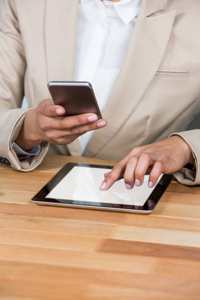 istock Mid-section of Businesswoman using mobile phone and digital tablet 652636402