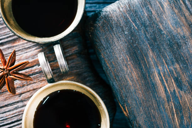 Pair of coffee on textured wood Pair of metallic cps of coffee and anise stars on textured brown wood. Close-up top view veining stock pictures, royalty-free photos & images