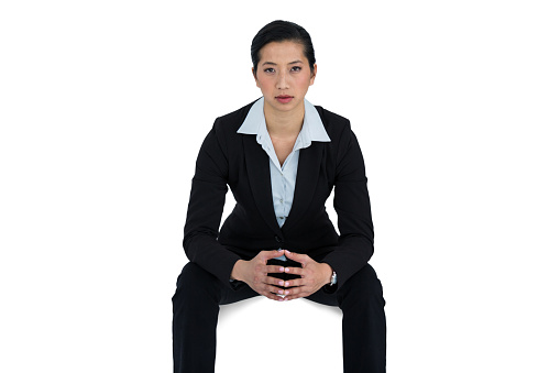 front view of a middle-aged woman sitting on a chair dressed in sportswear with her cross legged on white background