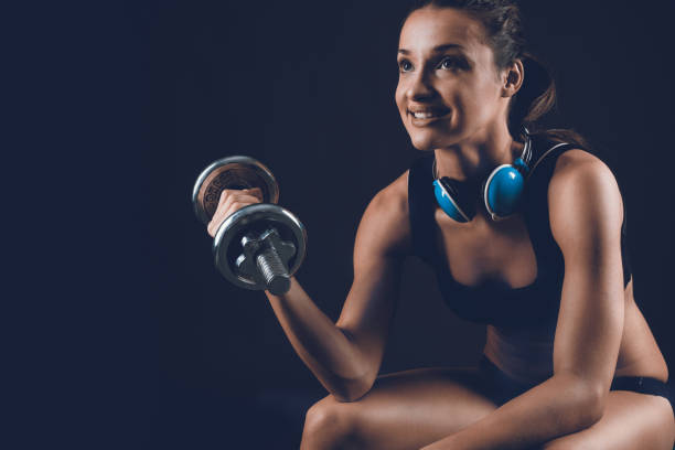 allenamento femminile sportivo fitness , pompando muscoli con manubri su sfondo nero - dumbbell weights weight training biceps femoris foto e immagini stock