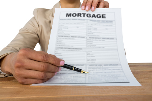 Mid section of businesswoman showing mortgage contract against white background