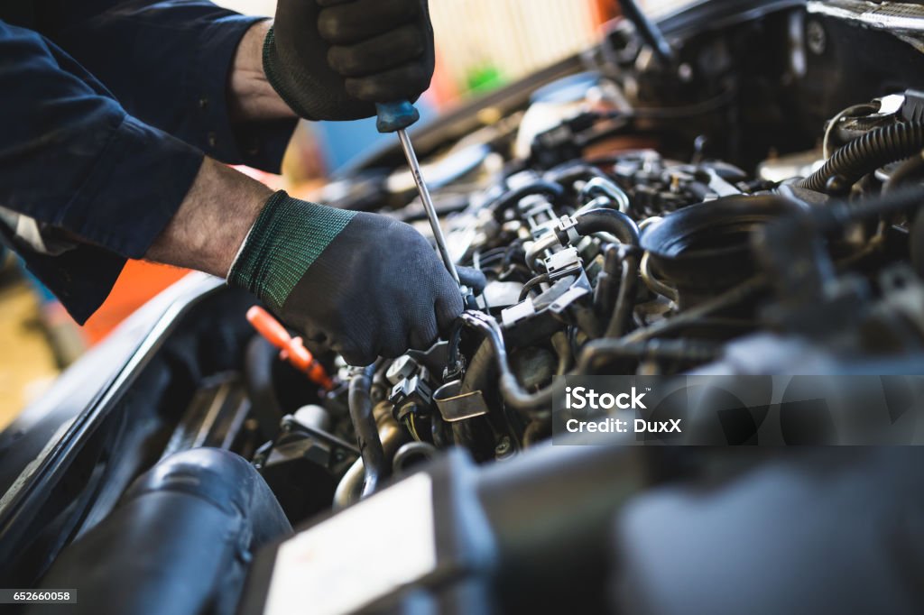 Auto mechanic service and repair Close up hands of unrecognizable mechanic doing car service and maintenance. Auto Repair Shop Stock Photo