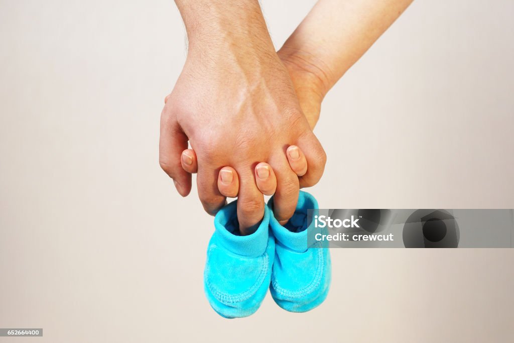 Happy young parents hold in their hands baby shoes of future child Happy father and mother hold in their hands baby shoes of their future first child Human Fertility Stock Photo