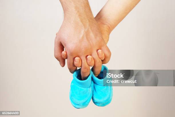 Happy Young Parents Hold In Their Hands Baby Shoes Of Future Child Stock Photo - Download Image Now