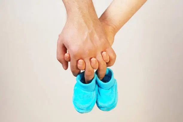 Happy father and mother hold in their hands baby shoes of their future first child