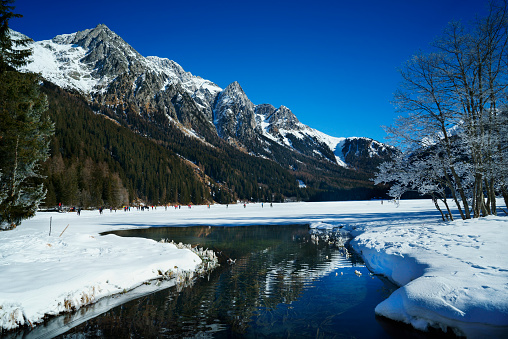 Snow covered mountain range and mirroring lake in scenic winter landscape in the Dolomite Alps. Antholz lake with reflecting water surface and clear sky. XXXL (Sony Alpha 7R)