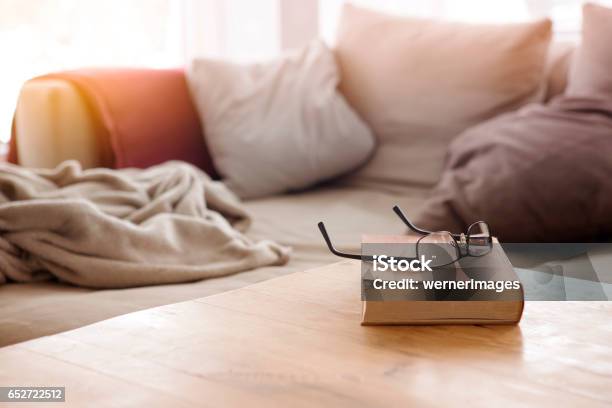 Book With Eyeglasses On Table In Front Of Couch Stock Photo - Download Image Now - Table, Living Room, Book