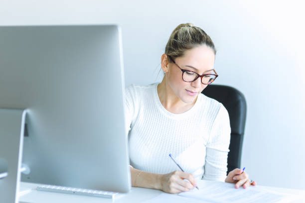istock Young woman using computer at desk in contemporary office 652725754