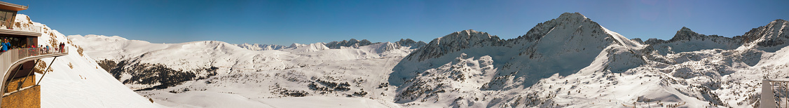 PYRENEES, ANDORRA - FEBRUARY 9, 2017: Panorama of alpine skiing slopes in Andorra. Cafe with unknown athletes on the edge of a shot. A view of tops of mountains in snow and ski slopes of the route