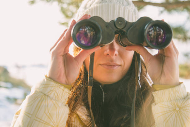 istock The girl in a White cap with a backpack in the winter in a forest looking through binoculars 652765034