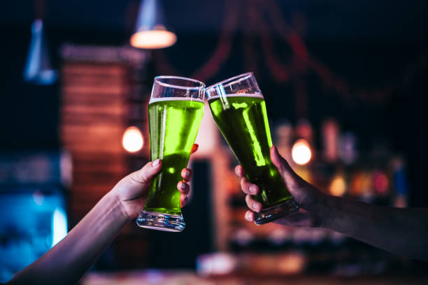 Two friends toasting with glasses of green beer at the pub with free space for your text. Beautiful background of the Beer Fest and St. Patrick's day. fine grain. Soft focus. Shallow DOF stock photo