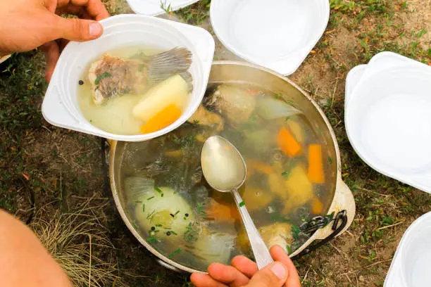 Serving soup from fish. Soup cooked in nature.