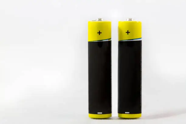 Two standing yellow black AAA alkaline batteries isolated on a white background with copy-space