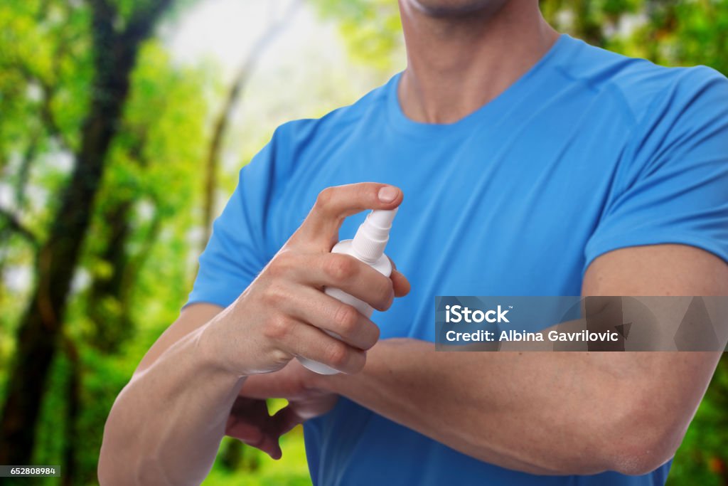 Mosquito repellent. Male using insect repellent spray from bootle in forest. Mosquito Stock Photo